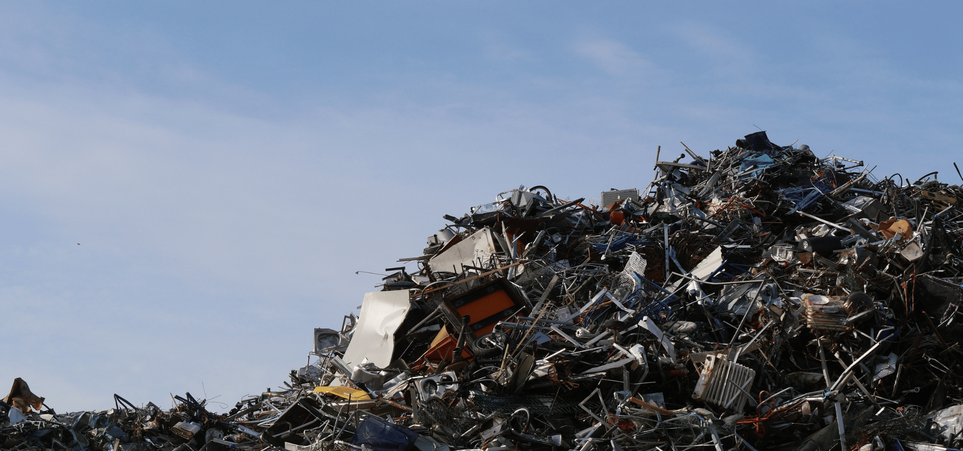 Recycled Industrial Metal Mountain under Expansive Blue Sky